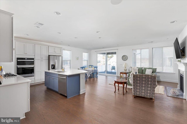 kitchen with dark wood-type flooring, a kitchen island, white cabinetry, appliances with stainless steel finishes, and sink