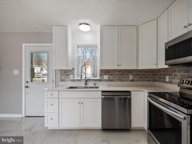 kitchen with stainless steel appliances, a textured ceiling, decorative backsplash, sink, and white cabinetry