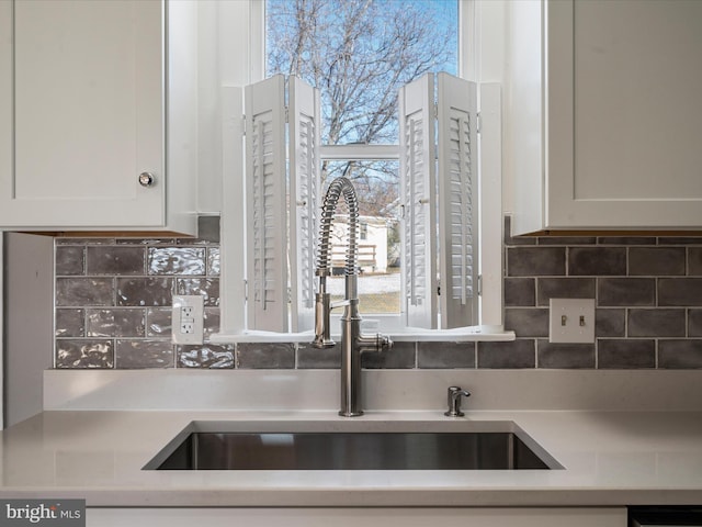 kitchen with white cabinets, decorative backsplash, and sink