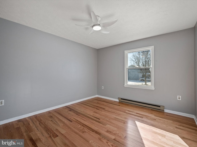 empty room with baseboard heating, light wood-type flooring, ceiling fan, and a textured ceiling