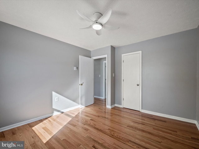 unfurnished bedroom with ceiling fan, light wood-type flooring, and a textured ceiling