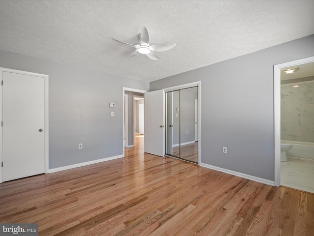 unfurnished bedroom featuring a textured ceiling, connected bathroom, ceiling fan, and light wood-type flooring