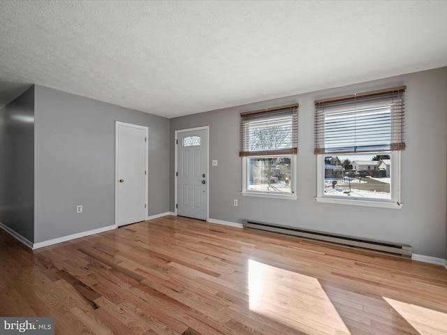 entrance foyer with a baseboard heating unit, a textured ceiling, and light hardwood / wood-style floors