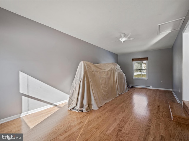 spare room featuring a baseboard heating unit, hardwood / wood-style floors, and ceiling fan