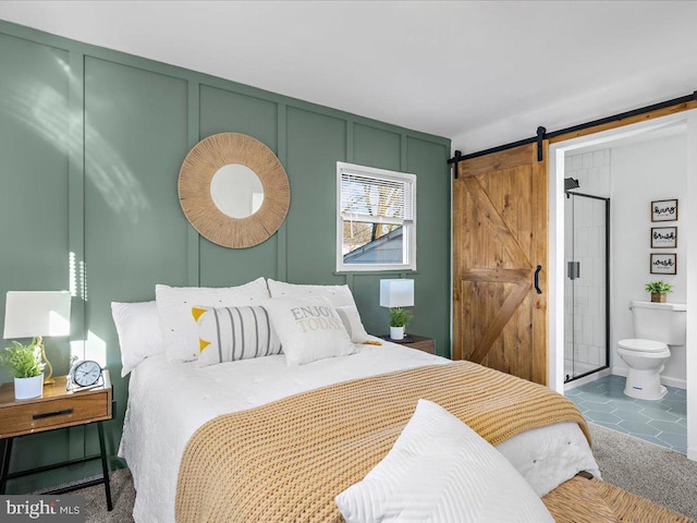 tiled bedroom featuring connected bathroom and a barn door