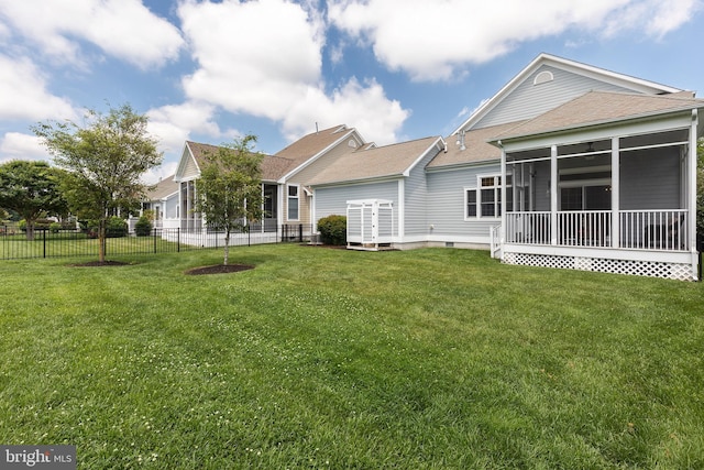 rear view of property featuring a lawn and a sunroom