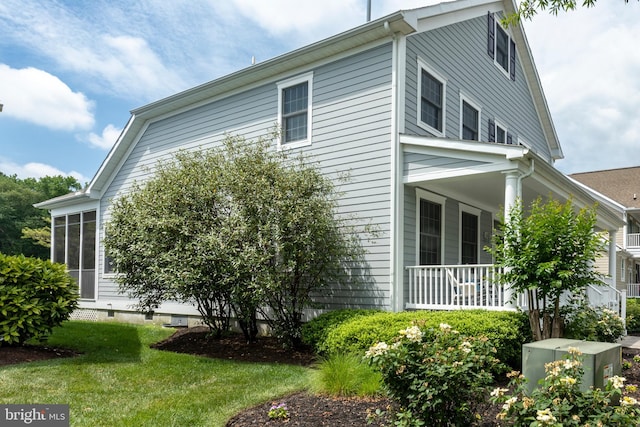 view of side of home with a lawn and a porch