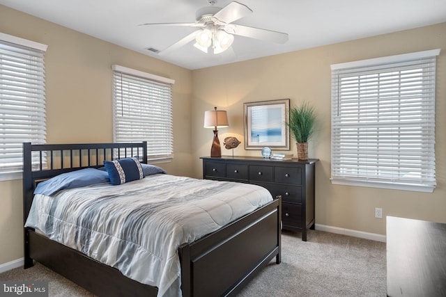 bedroom featuring multiple windows, light colored carpet, and ceiling fan