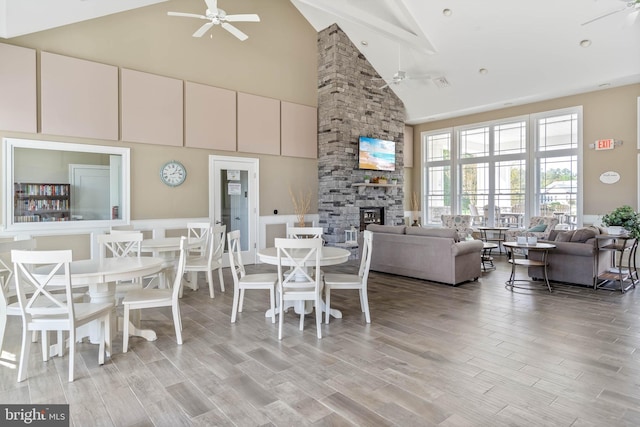 dining area featuring ceiling fan, a fireplace, and high vaulted ceiling