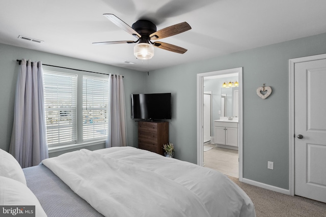 bedroom featuring ceiling fan, sink, light colored carpet, and ensuite bath