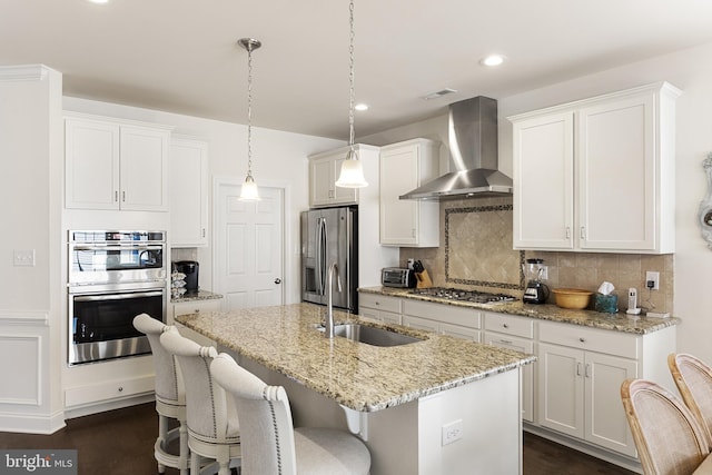 kitchen featuring wall chimney exhaust hood, sink, white cabinetry, and stainless steel appliances