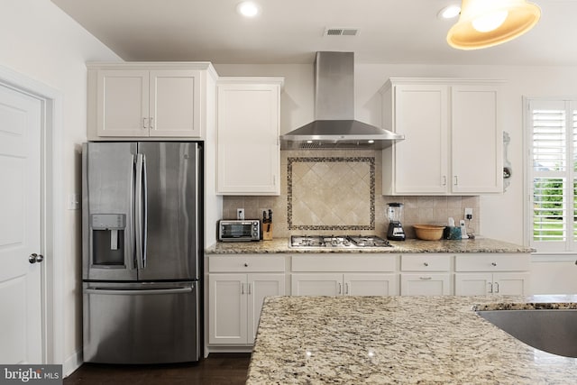 kitchen featuring white cabinets, light stone counters, wall chimney exhaust hood, and stainless steel appliances