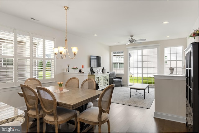 dining space with ceiling fan with notable chandelier and dark hardwood / wood-style flooring