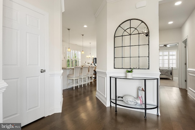 hall with plenty of natural light, dark wood-type flooring, and an inviting chandelier