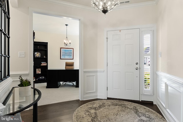 foyer entrance with crown molding, dark wood-type flooring, and an inviting chandelier