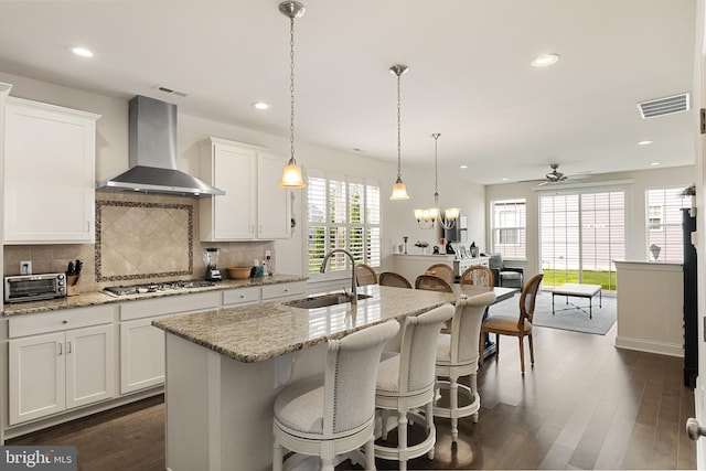 kitchen with white cabinetry, wall chimney range hood, sink, and stainless steel gas cooktop