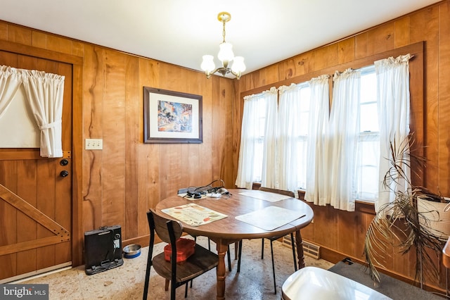 dining space featuring wood walls and an inviting chandelier