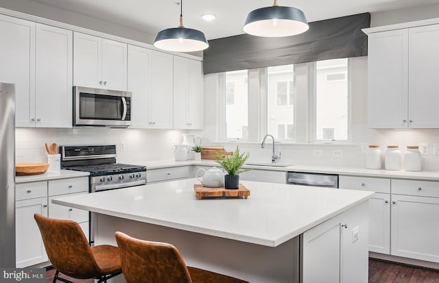 kitchen featuring white cabinetry, hanging light fixtures, stainless steel appliances, and sink