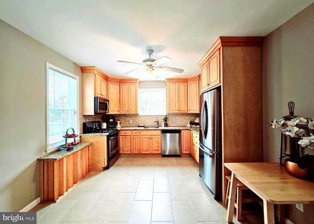 kitchen with light stone countertops, backsplash, appliances with stainless steel finishes, and plenty of natural light