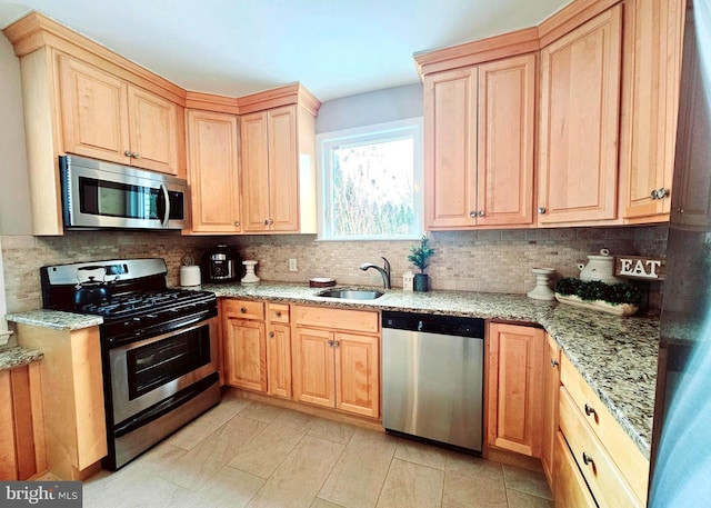 kitchen with light stone countertops, appliances with stainless steel finishes, tasteful backsplash, sink, and light tile patterned floors