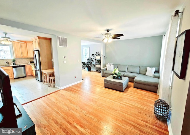 living room with sink, ceiling fan, and light hardwood / wood-style flooring