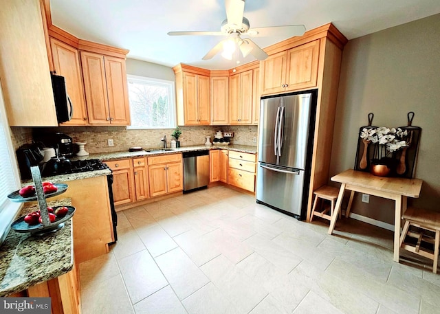 kitchen featuring stainless steel appliances, decorative backsplash, sink, ceiling fan, and light stone counters