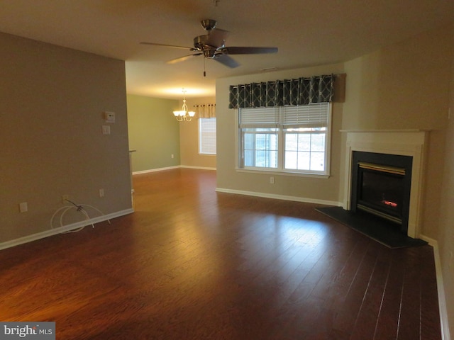 unfurnished living room with ceiling fan with notable chandelier and dark hardwood / wood-style flooring