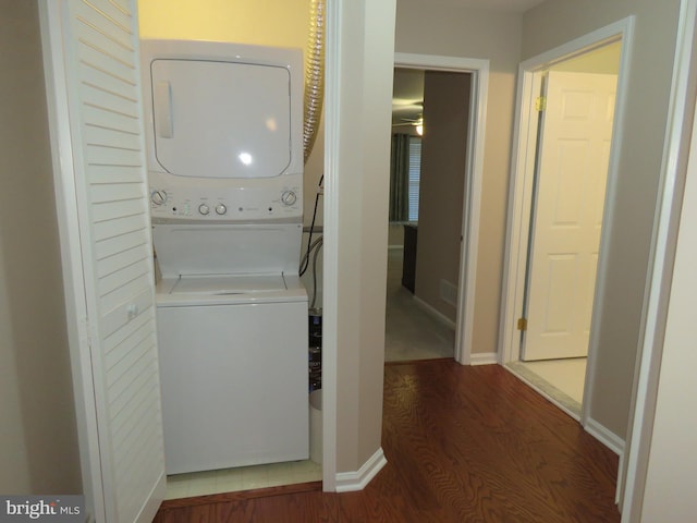 washroom with hardwood / wood-style floors and stacked washer / drying machine