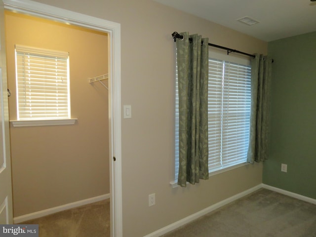 unfurnished bedroom featuring light carpet, a walk in closet, and a closet