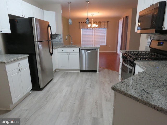 kitchen with light stone countertops, white cabinetry, sink, stainless steel appliances, and pendant lighting