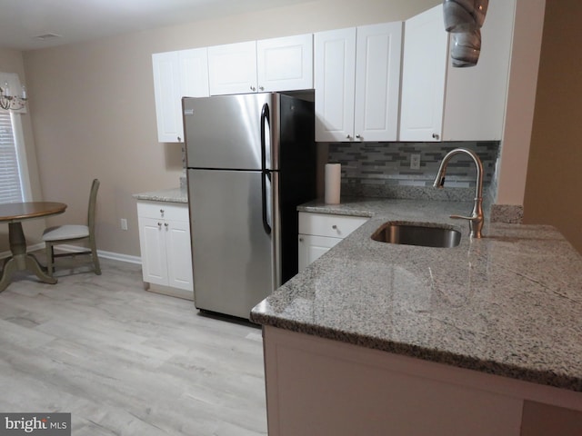 kitchen with white cabinets, backsplash, stainless steel refrigerator, and sink