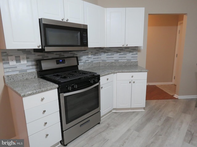 kitchen with decorative backsplash, light stone counters, white cabinetry, and appliances with stainless steel finishes