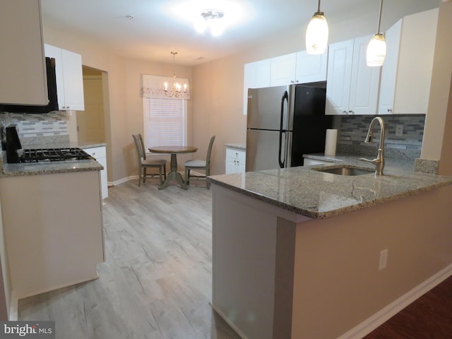 kitchen featuring white cabinetry, kitchen peninsula, stainless steel fridge, and pendant lighting