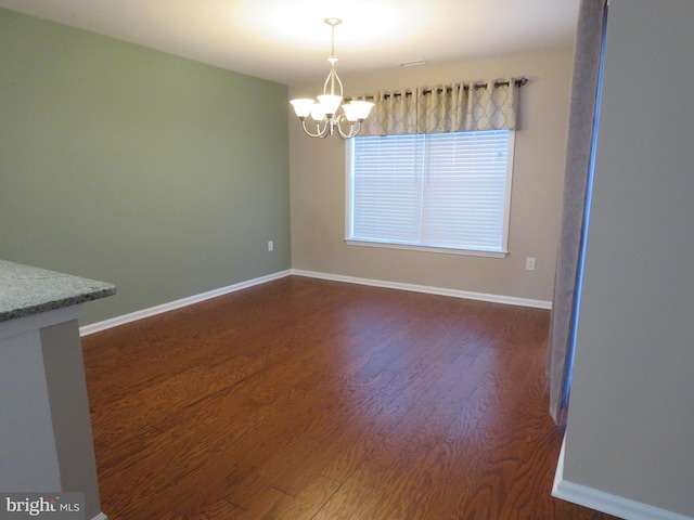 unfurnished dining area with dark hardwood / wood-style floors and a notable chandelier