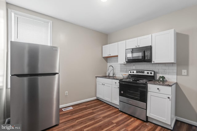 kitchen with backsplash, white cabinetry, stainless steel appliances, and dark stone countertops