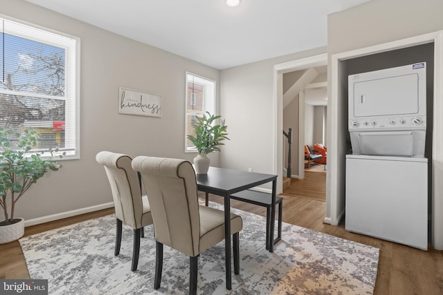 dining area featuring wood-type flooring and stacked washer and clothes dryer