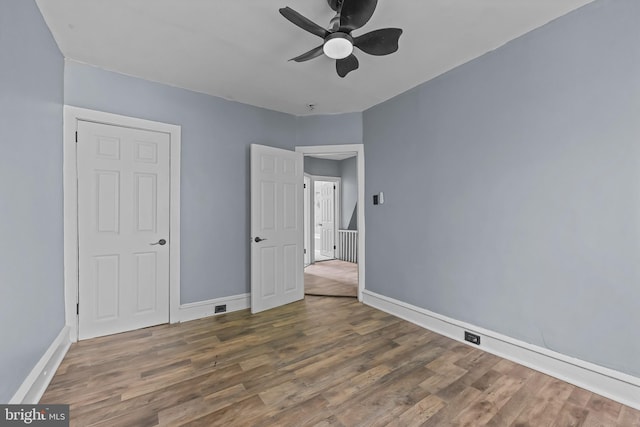 unfurnished bedroom with ceiling fan, dark hardwood / wood-style floors, and a closet