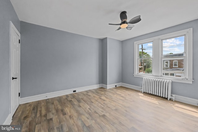 unfurnished room featuring wood-type flooring, radiator, and ceiling fan