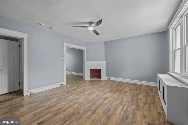 unfurnished living room with ceiling fan, dark hardwood / wood-style floors, and a brick fireplace