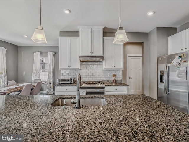 kitchen featuring decorative light fixtures, dark stone countertops, sink, appliances with stainless steel finishes, and white cabinets