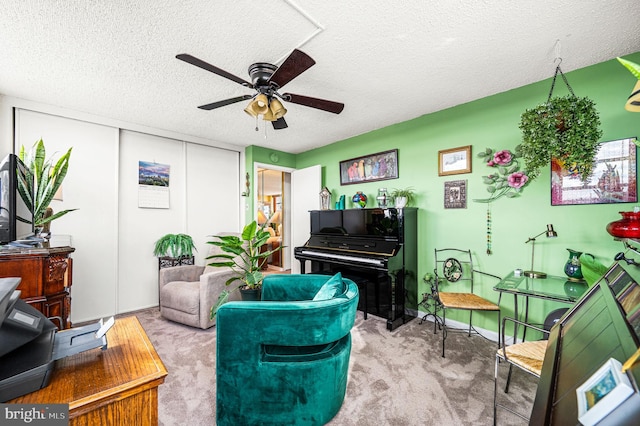 living room with ceiling fan, carpet floors, and a textured ceiling