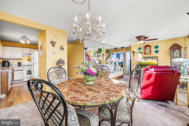 carpeted dining room featuring a textured ceiling and ceiling fan with notable chandelier