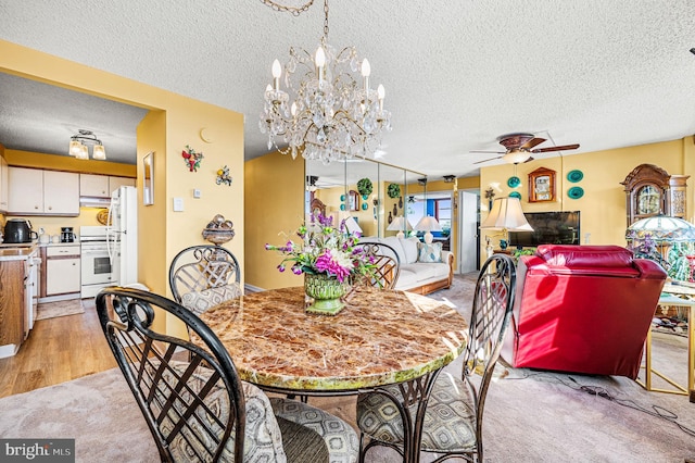 carpeted dining room featuring a textured ceiling and ceiling fan with notable chandelier