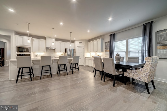 dining room featuring sink and light hardwood / wood-style flooring