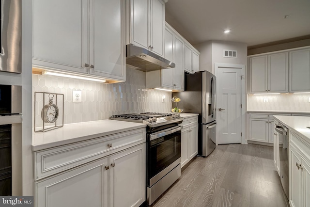 kitchen featuring white cabinetry, backsplash, stainless steel appliances, and light hardwood / wood-style floors