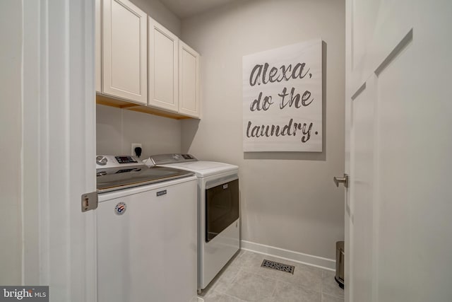 washroom featuring cabinets, washer and clothes dryer, and light tile patterned floors