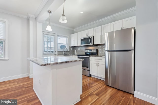 kitchen with white cabinetry, light stone counters, appliances with stainless steel finishes, hardwood / wood-style flooring, and backsplash