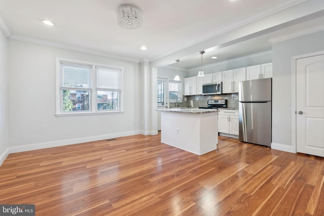 kitchen with stainless steel appliances, decorative light fixtures, light stone countertops, and white cabinets