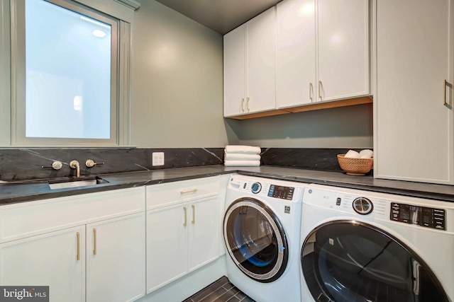 clothes washing area featuring washing machine and clothes dryer, sink, and cabinets