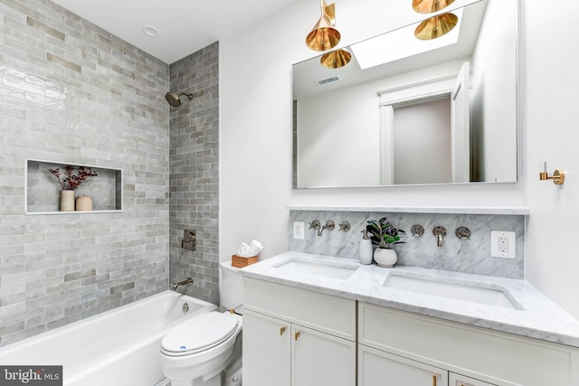 full bathroom with a skylight, backsplash, toilet, vanity, and tiled shower / bath